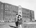 Two primary school students standing in front of Nesbitt School in the Rosemont district of Montreal (K. Nakashima).
