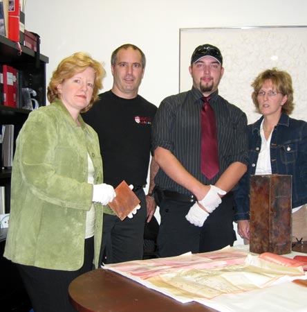 From left: Associate Secretary-General and University Archivist Johanne Pelletier, Waste Management Program manager Claude Lahaie, McGill Campus Security officer Sergeant Mathieu Racette, and Director of Security Louise Savard gather around the opened time capsule, its contents on display on the table. Photo by David Kemper/McGill University Archives.